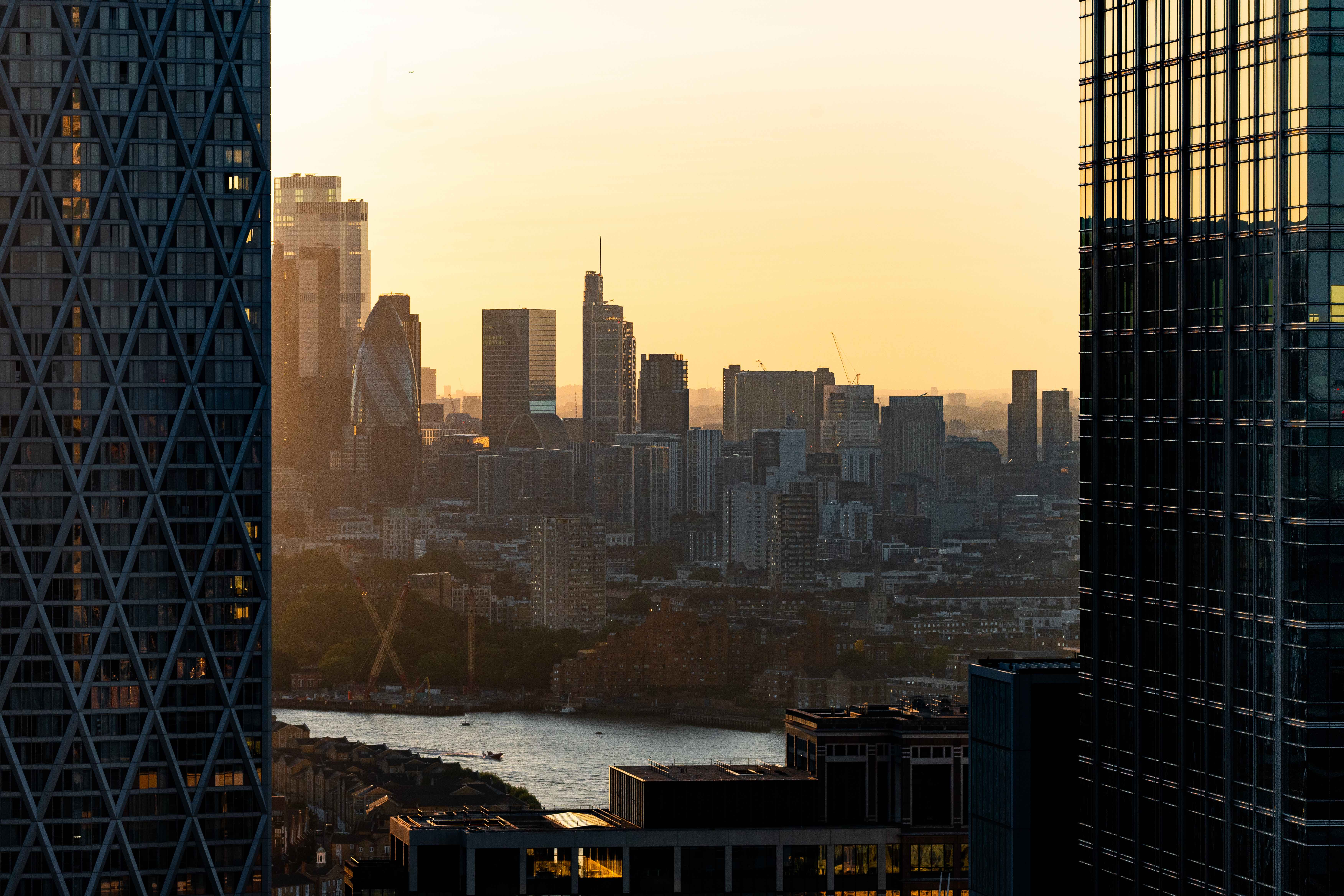 Golden hour aerial view of the City of London skyline from Canary Wharf, with the Thames below